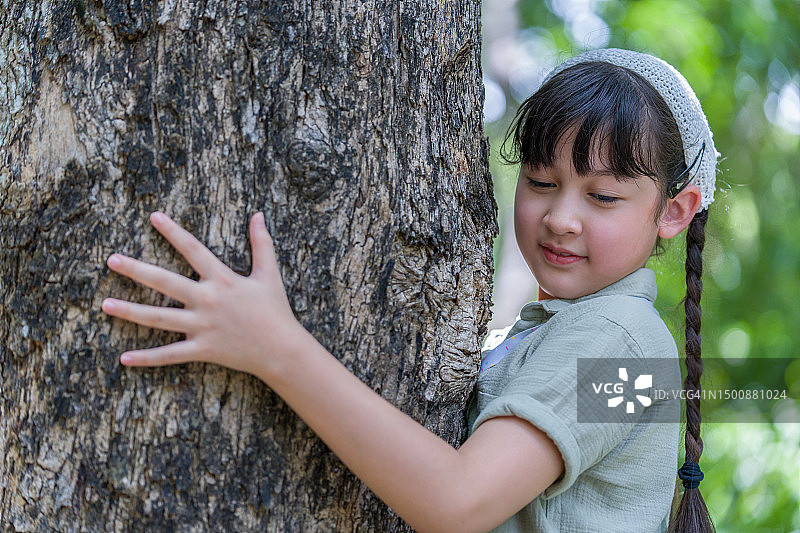 闭着眼睛拥抱树的年轻女孩图片素材