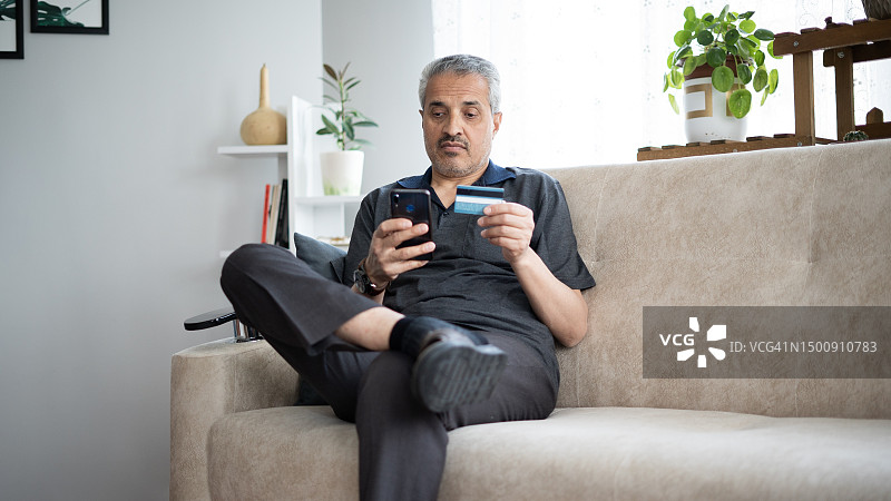 老年男人在家用手机信用卡购物图片素材