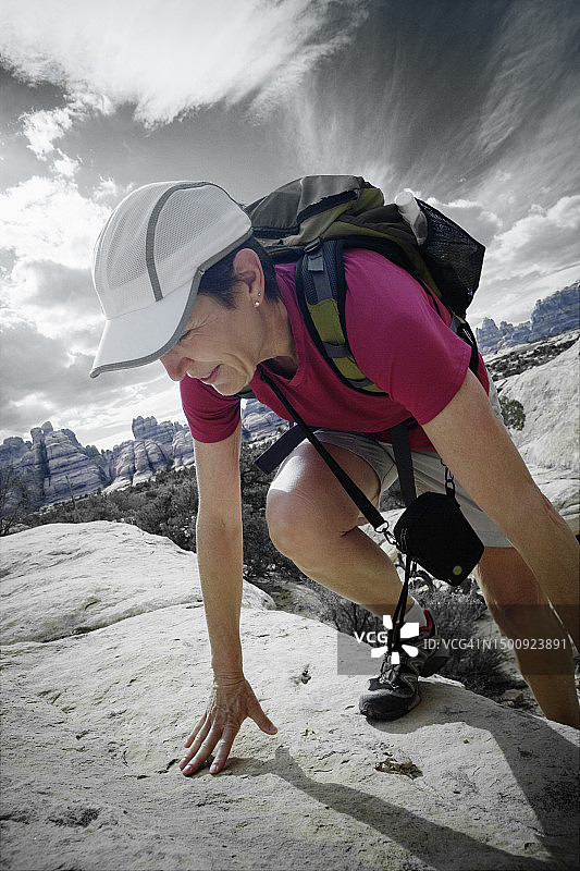 女徒步者攀登峡谷地国家公园的岩架图片素材