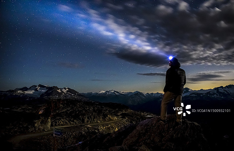 男人夜晚在山顶用头灯照天空，加拿大惠斯勒图片素材
