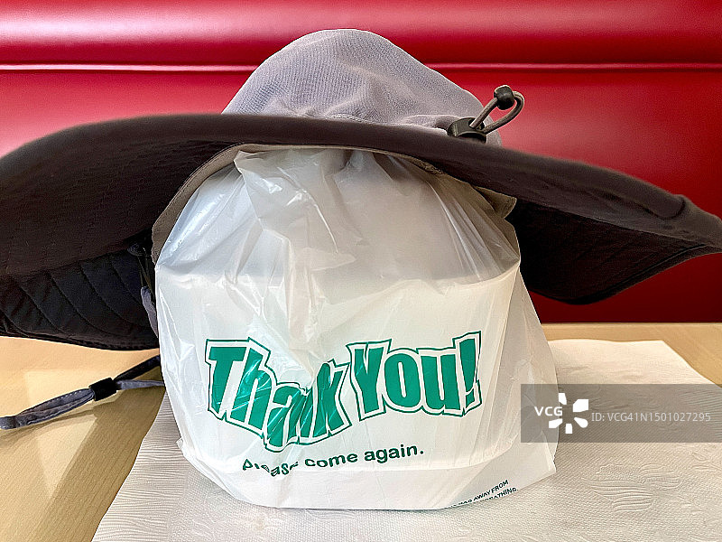 桌子上放着装帽子的外卖袋图片素材