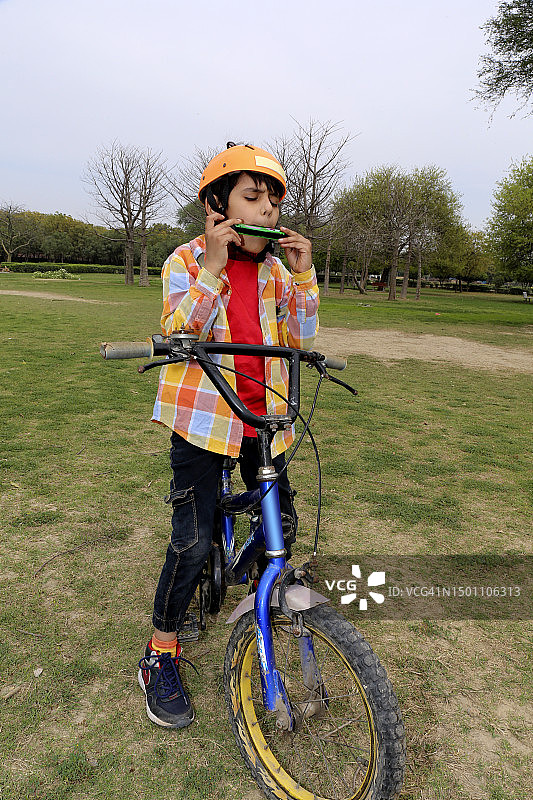 在公园里骑自行车吹口琴的男孩特写图片素材