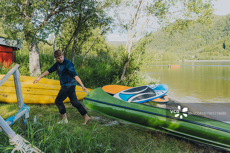 在挪威风景如画的森林湖边划独木舟的男人图片素材
