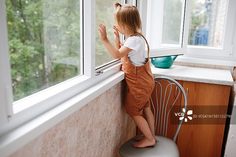 探索窗户：好奇的幼儿与蚊帐互动，儿童安全防护图片素材
