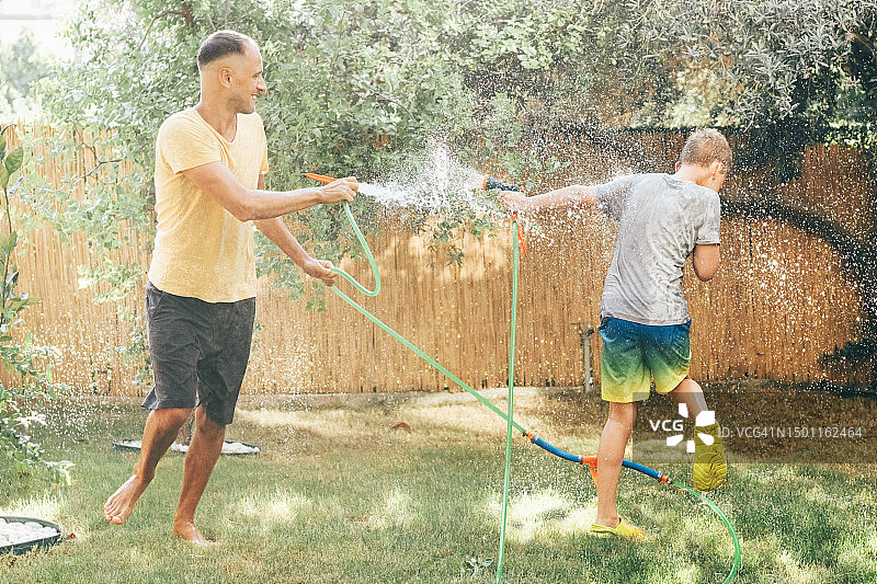 父亲在后院和儿子玩水嬉戏图片素材