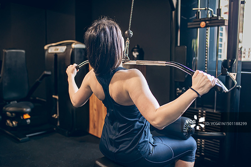 女人在健身房使用高位下拉器械锻炼图片素材