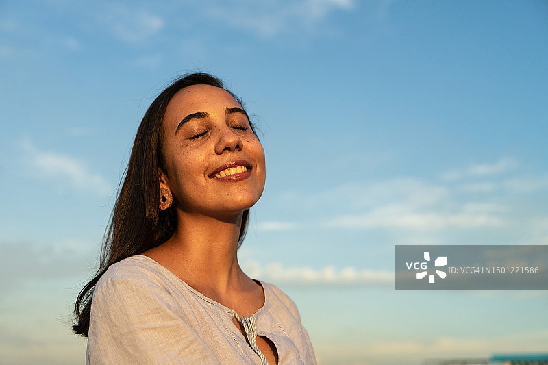 年轻女子在户外闭着眼睛呼吸新鲜空气图片素材