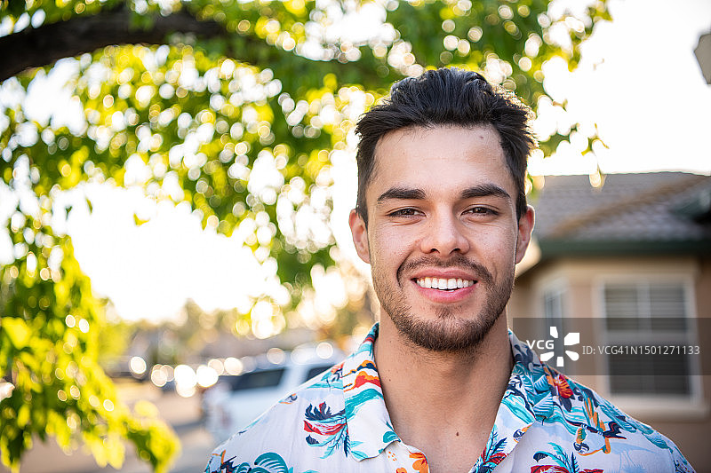 在自家前院对着镜头微笑的年轻西班牙裔男子图片素材