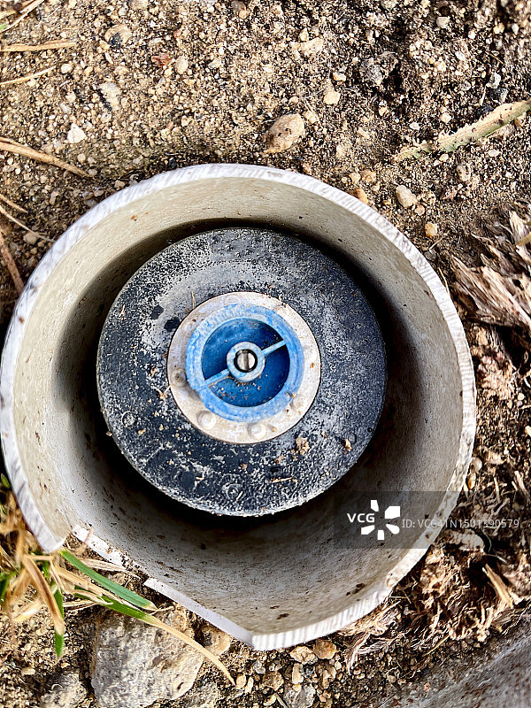 被泥土和草包围的损坏PVC管中的喷水器图片素材