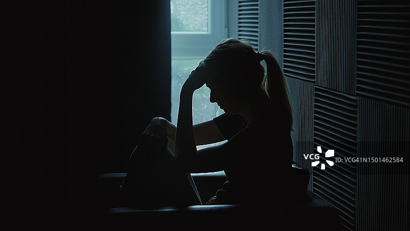 女孩坐在黑暗的房间里，遭受精神崩溃——抑郁症图片素材