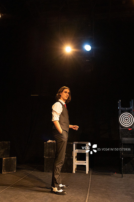 英俊的年轻男子穿着复古西装，站在业余剧院舞台上的侧视图图片素材