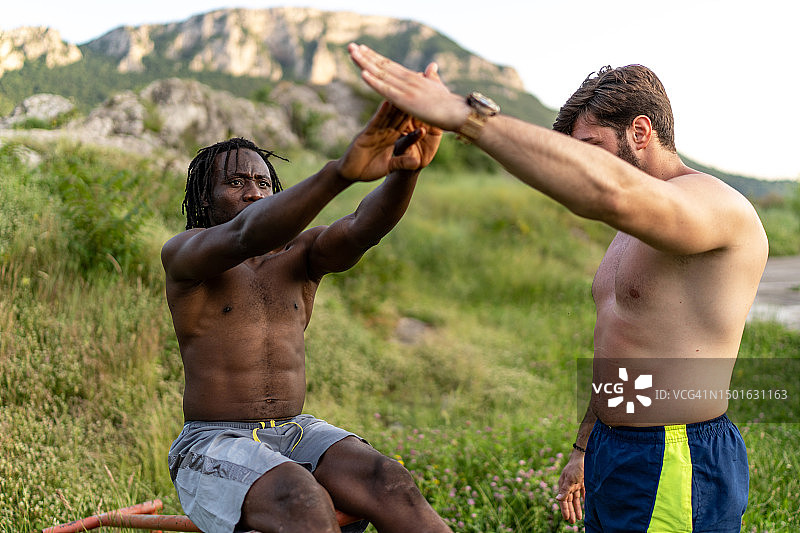 在户外健身房与私人教练一起进行腹部锻炼图片素材