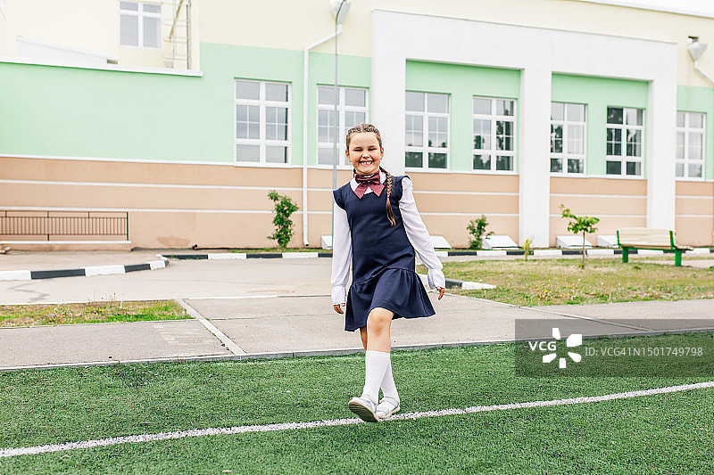 快乐的女学生走在草地上，对着镜头开怀大笑图片素材