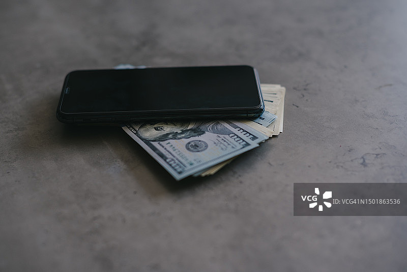 灰色背景上的手机和钱，支付和储蓄概念图片素材