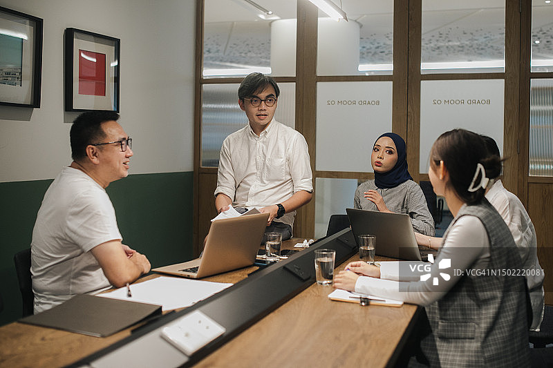 中国男子在会议室主持会议，向多民族同事介绍情况图片素材