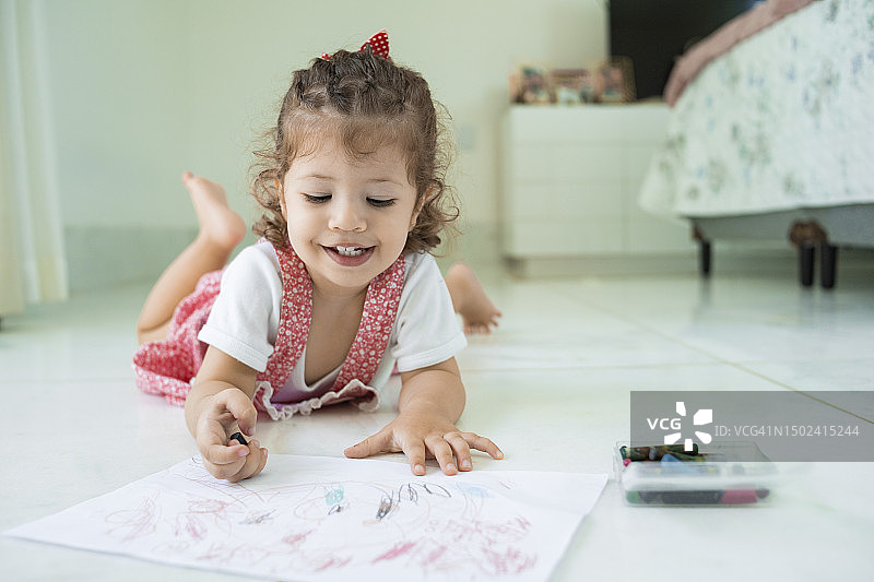 孩子躺在卧室地板上画画图片素材
