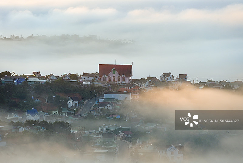 阳光下雾气笼罩的教堂与小村庄图片素材