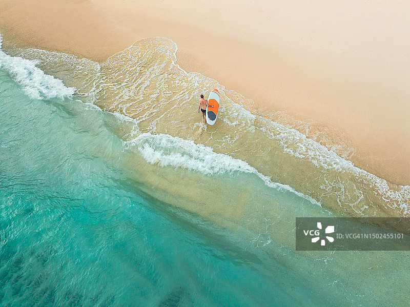 无人机拍摄：印度尼西亚巴厘岛乌鲁瓦图，男子在印度洋中携带桨板图片素材