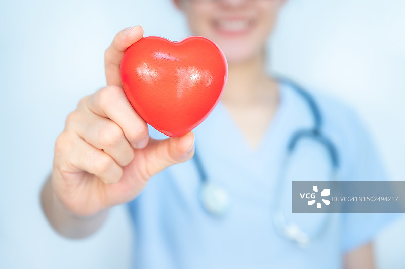 医护人员手持并向镜头展示一颗橡胶红心的裁剪镜头。图片素材