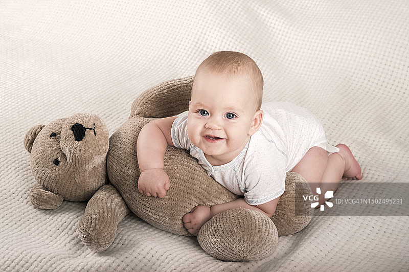 七个月大新生婴儿和玩具熊在床上特写图片素材
