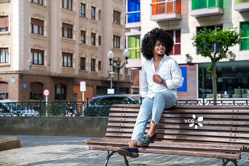 快乐的英俊拉丁裔男人：在色彩缤纷的城市背景中展现现代优雅图片素材