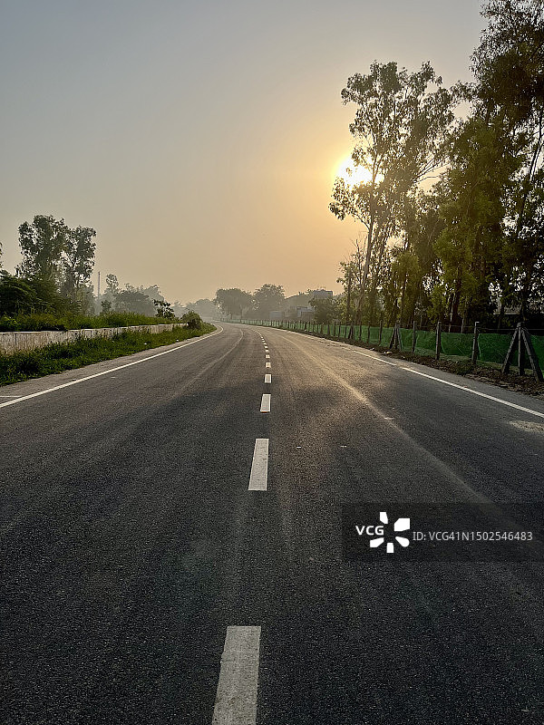 日落时分，印度哈里亚纳邦法里达巴德空旷的道路图片素材