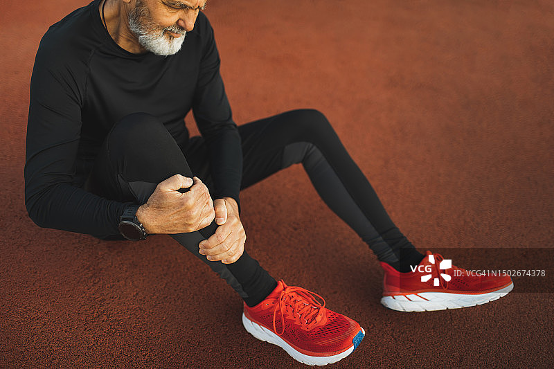 老年男人在运动跑道上跑步时腿部受伤，韧带或肌腱扭伤图片素材