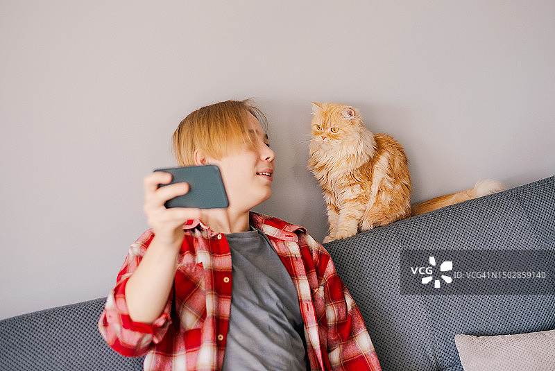 在家与可爱的姜色猫咪自拍的男孩图片素材