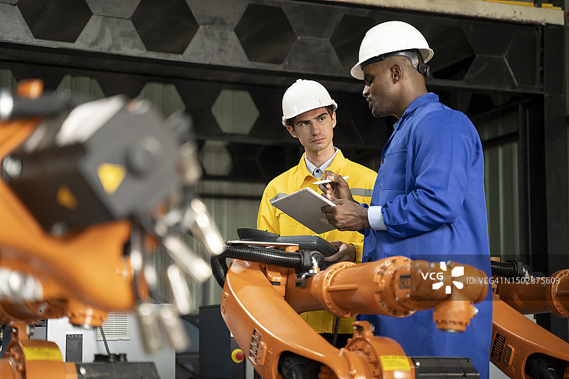 工程师团队在自动化工厂维修焊接机器人图片素材
