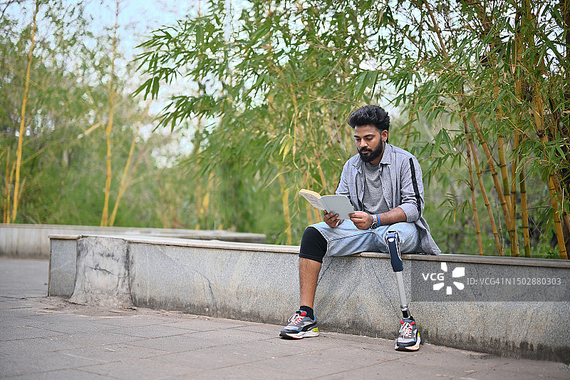 装有假肢的男人在自然中读书沉思图片素材