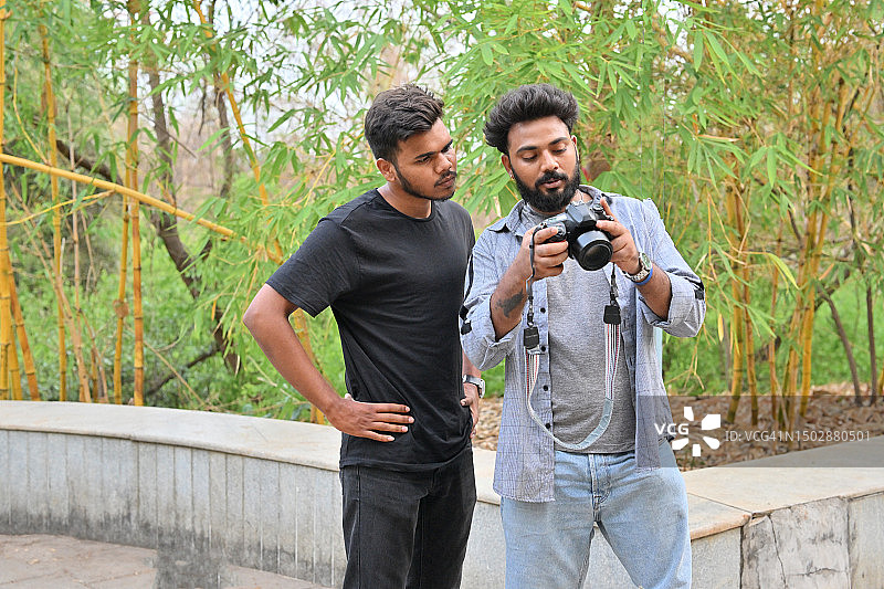带着假肢腿的男人和他的朋友在相机上查看照片图片素材