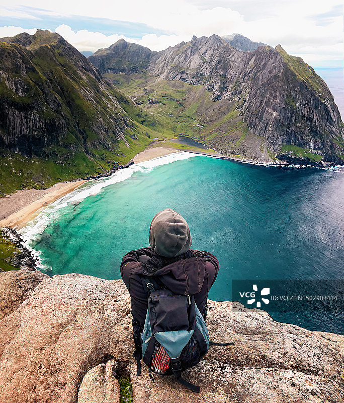 徒步旅行者在罗弗敦群岛的悬崖上欣赏Kvalvika海滩的壮丽景色图片素材