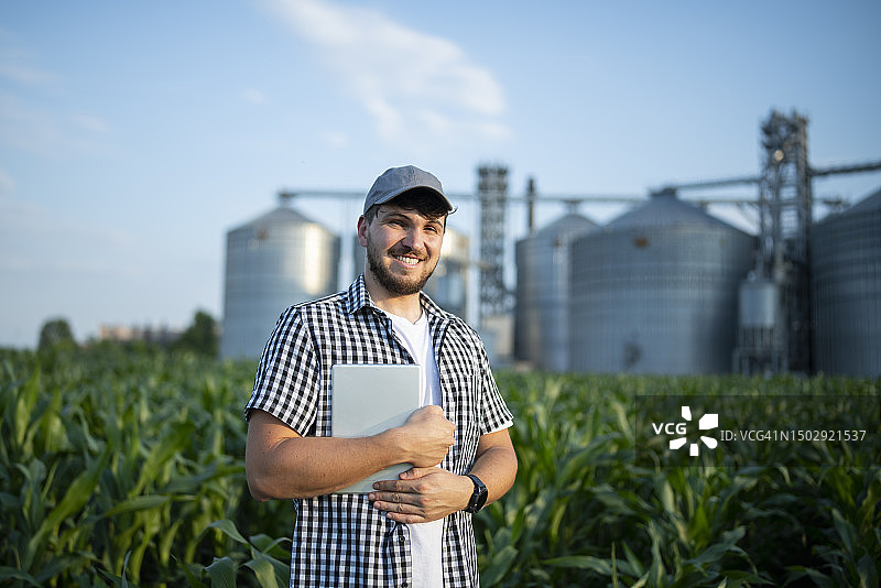 在玉米地里使用科技的微笑农民肖像图片素材