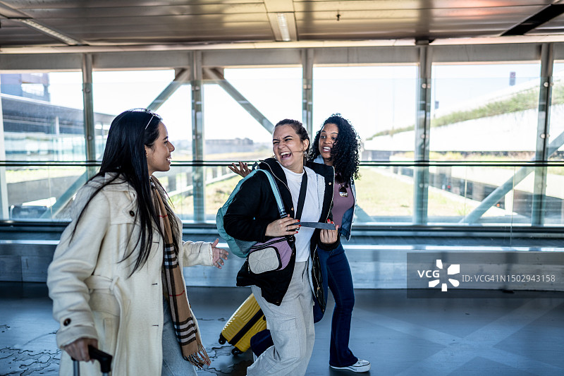 在机场高架走道上边走边聊天的快乐女性朋友们图片素材