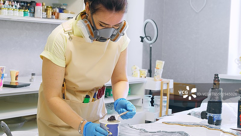 戴着防护面罩的女人专注于制作迷人的树脂杰作图片素材