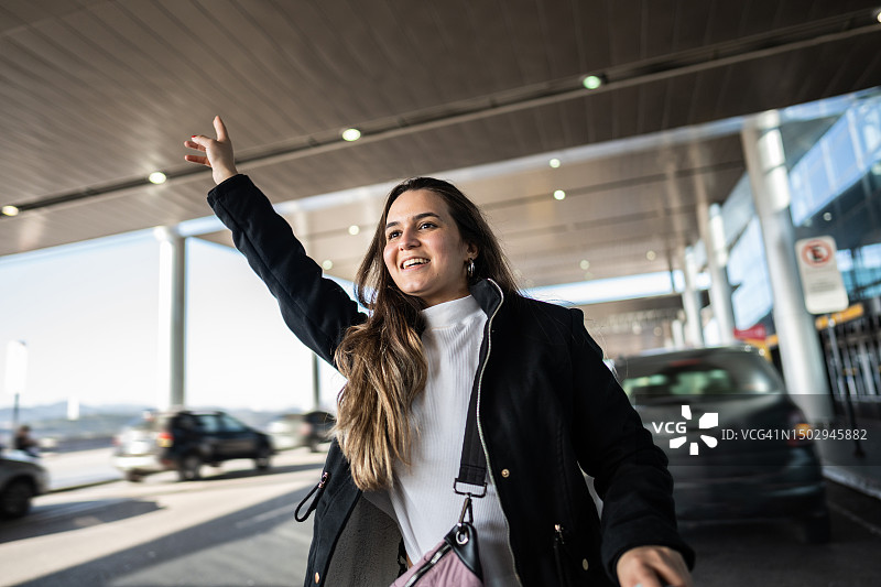年轻女子在机场叫出租车图片素材