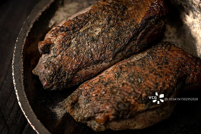 烤鸭胸肉、煎鸭肉片、金属盘中的肉、木质背景（特写，俯视，留白，柔焦）图片素材