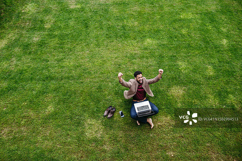 庆祝成功交易，赤脚坐在草坪上的商人图片素材