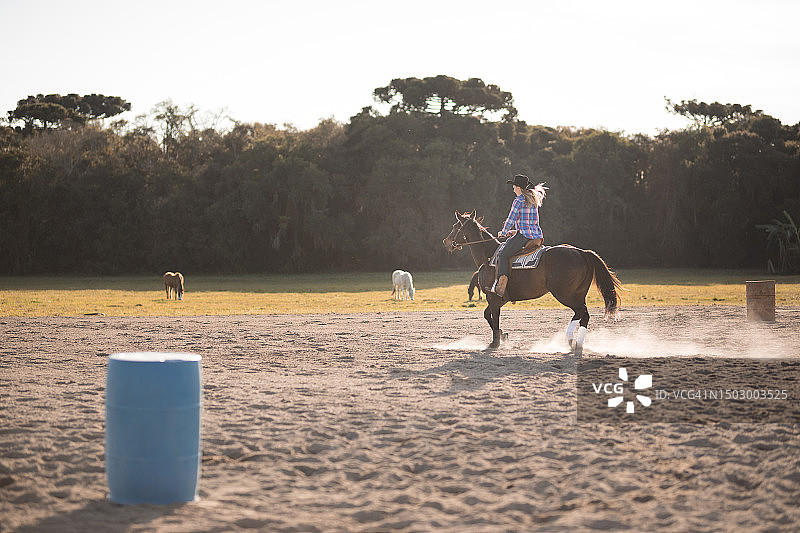 女人骑马进行绕桶赛训练图片素材