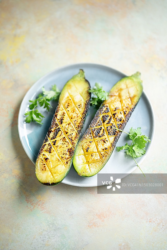 盘子上烤制的一半西葫芦（彩色背景）图片素材