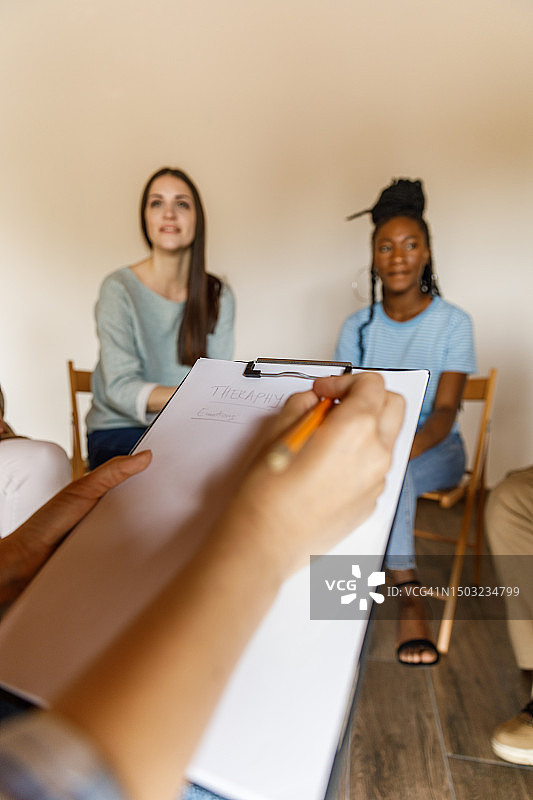 女理疗师在团体治疗期间做笔记图片素材
