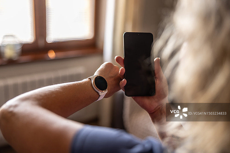 妇女在手机和手表上查看运动数据图片素材