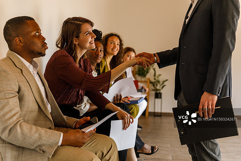 经理与排队等候的求职面试者握手图片素材