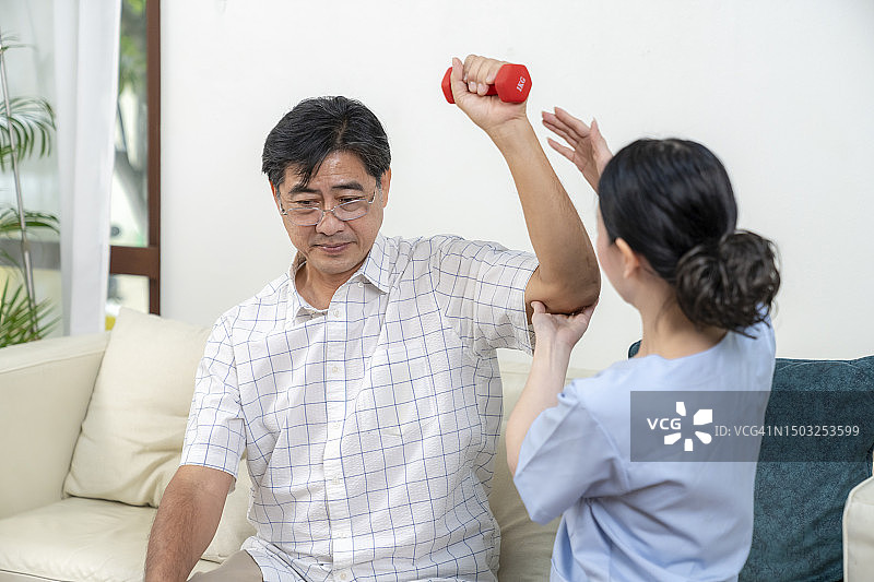 护士在家中帮助老人进行物理治疗。图片素材