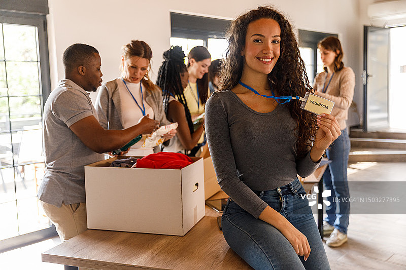 年轻女子向您展示她的志愿者身份证，喜笑颜开图片素材