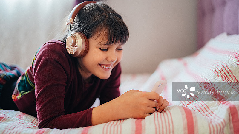 小女孩在床上和朋友视频通话图片素材