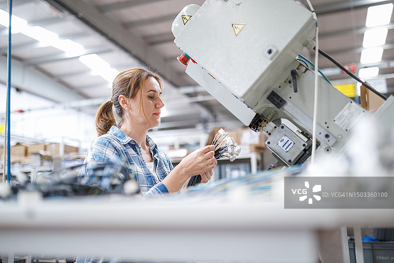 在工厂使用制造设备的女工图片素材