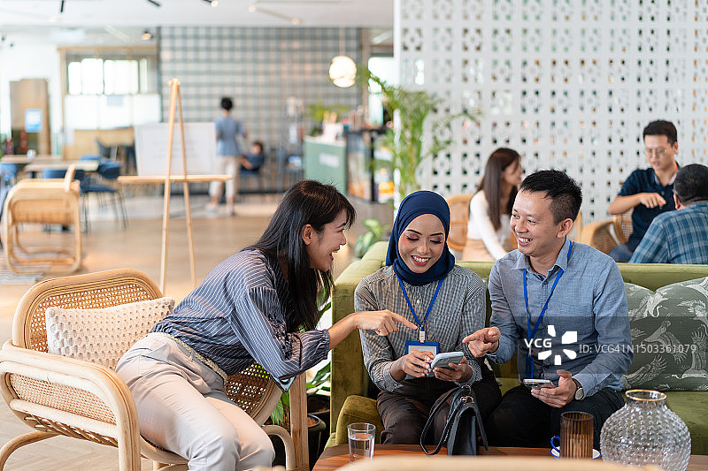 多种族亚洲同事在午休时间一起看智能手机，分享快乐时光图片素材