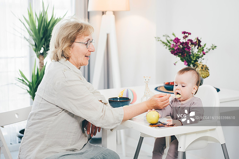 祖母在厨房里喂女婴图片素材
