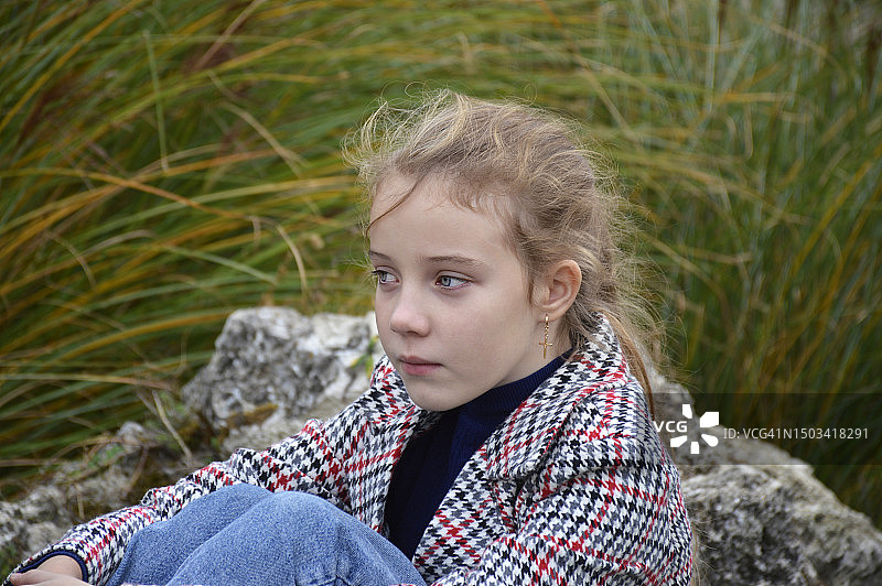 坐在岩石上，看向远方的可爱女孩，摩尔多瓦图片素材